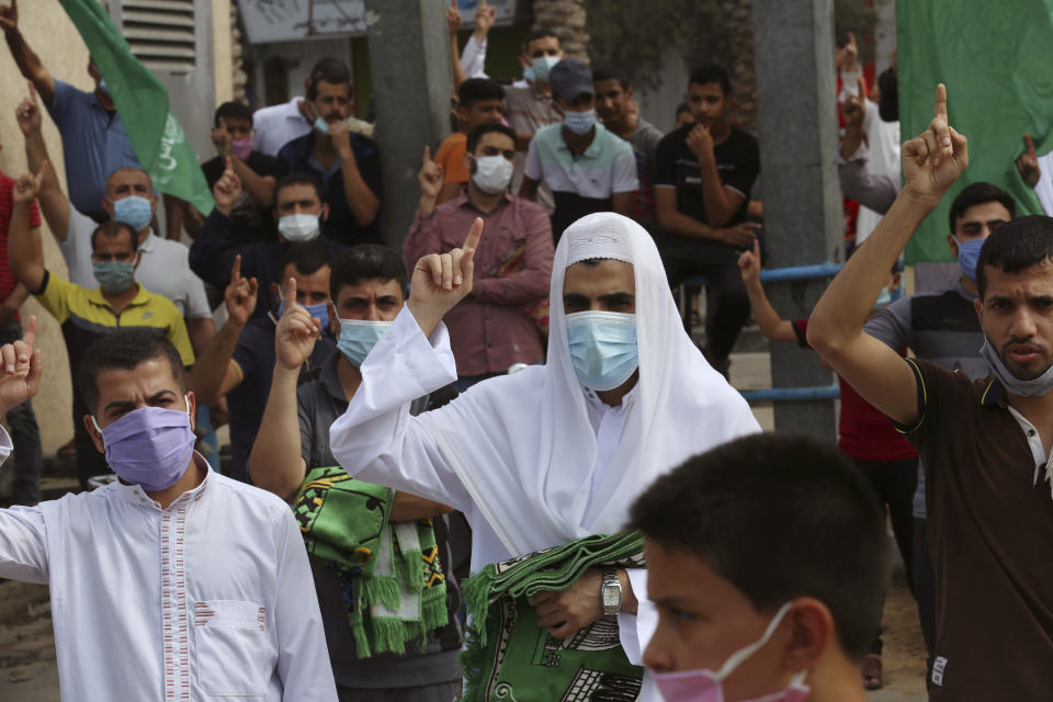 Hamas supporters wear face masks raise their fingers up while chant anti slogans during a protest against French President Emmanuel Macron and the publishing of caricatures of the Muslim Prophet Muhammad they deem blasphemous, at the main road of Jebaliya refugee camp, Gaza Strip, Friday, Oct. 30, 2020. (AP Photo/Adel Hana)