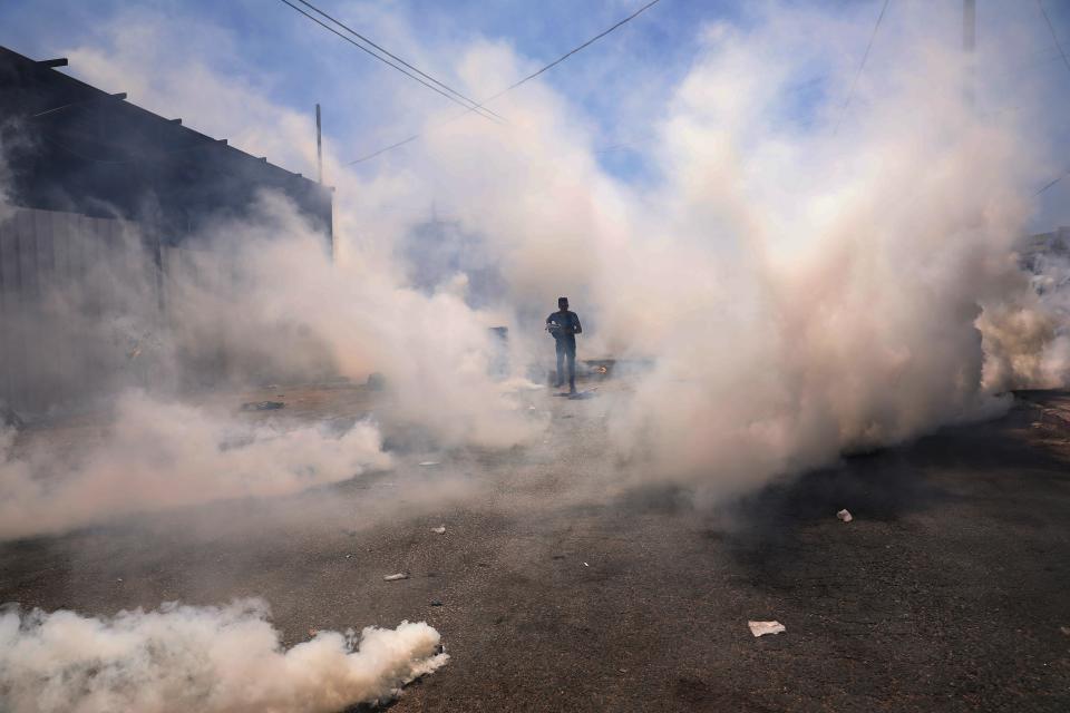 A Palestinian protester seeks cover from tear gas during clashes with Israeli troops after a protest against Israeli settlements at Beta village near the West Bank City of Nablus (EPA)