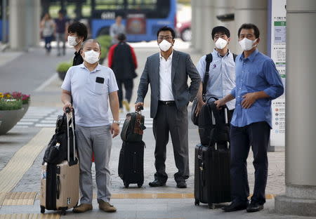 Passengers wearing masks to prevent contracting Middle East Respiratory Syndrome (MERS) wait for crosswalk traffic lights at Gimpo International Airport in Seoul, South Korea, June 17, 2015. REUTERS/Kim Hong-Ji