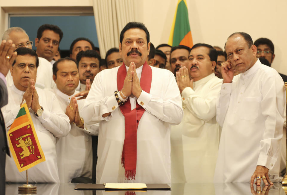 Sri Lanka's newly appointed prime minister Mahinda Rajapaksa, center, prays along with his supporting law makers during the duties assuming ceremony in Colombo, Sri Lanka, Monday, Oct. 29, 2018. (AP Photo/Lahiru Harshana)