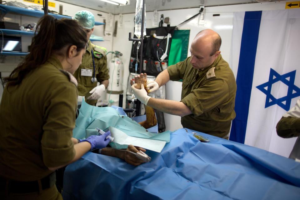 Members of the Israeli army medical staff tend to a Syrian man who was wounded in the ongoing violence in Syria, in a military hospital located in the Golan Heights near the border with Syria on Tuesday, Feb. 18, 2014. Since the Syrian conflict erupted almost three years ago hundreds of Syrians have received treatment in Israeli hospitals.(AP Photo/Menahem Kahana, Pool)