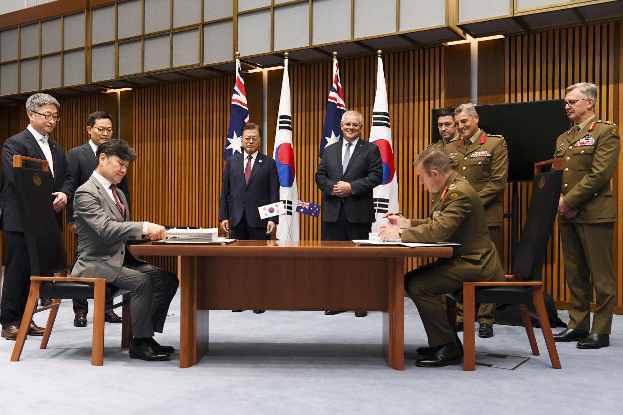 South Korean President Moon Jae-in, center left, and Australian Prime Minister Scott Morrison, center right, witness representatives of Hanwha Group, left, and members of the Australian Defence Force during a signing ceremony at Parliament House, in Canberra, Australia, Monday, Dec. 13, 2021. Moon is on a two-day official visit to Australia. (Lukas Coch/Pool Photo via AP)