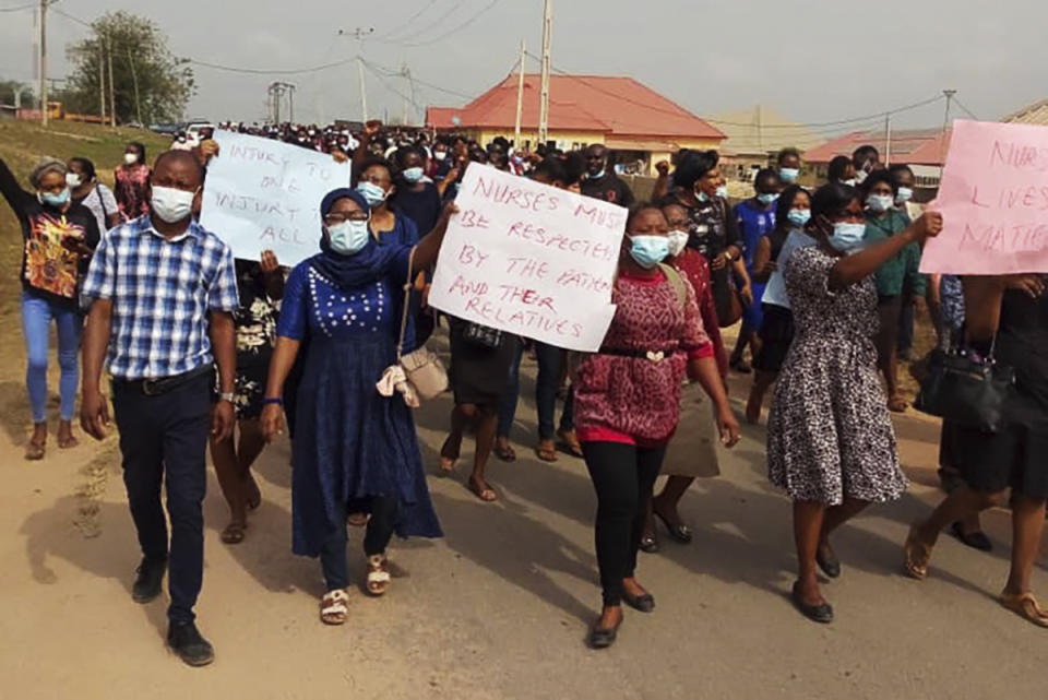 Nurses and supporters in Owo, Nigeria, participate in a march on Feb. 7, 2021, demanding the Federal Medical Centre in Owo provide security for its staff after two nurses were were attacked by the family of a deceased COVID-19 patient. A new report identified hundreds of threats or acts of violence against health care workers and facilities last year linked to fear or frustration around the coronavirus. (Tochukwu Q.O. via AP)