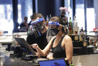 Bartenders were masks and face shields as they work at Slater's 50|50 in Wednesday, July 1, 2020, in Santa Clarita, Calif. California Gov. Gavin Newsom has ordered a three-week closure of bars, indoor dining and indoor operations of several other types of businesses in various counties, including Los Angeles, as the state deals with increasing coronavirus cases and hospitalizations. (AP Photo/Marcio Jose Sanchez)