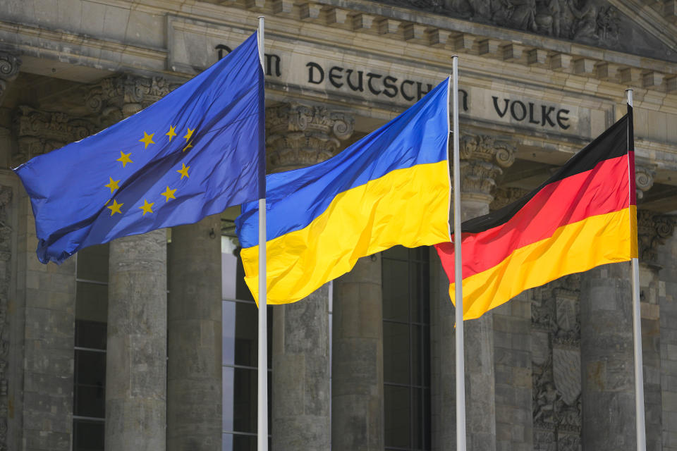The Ukrainian national flag waves betwen the Europa fag, left, and the German national flag, right, in front of the Reichstag building during a debate at the German parliament Bundestag in Berlin, Germany, Wednesday, June 1, 2022. The inscription reads: 'The German People'. (AP Photo/Markus Schreiber)