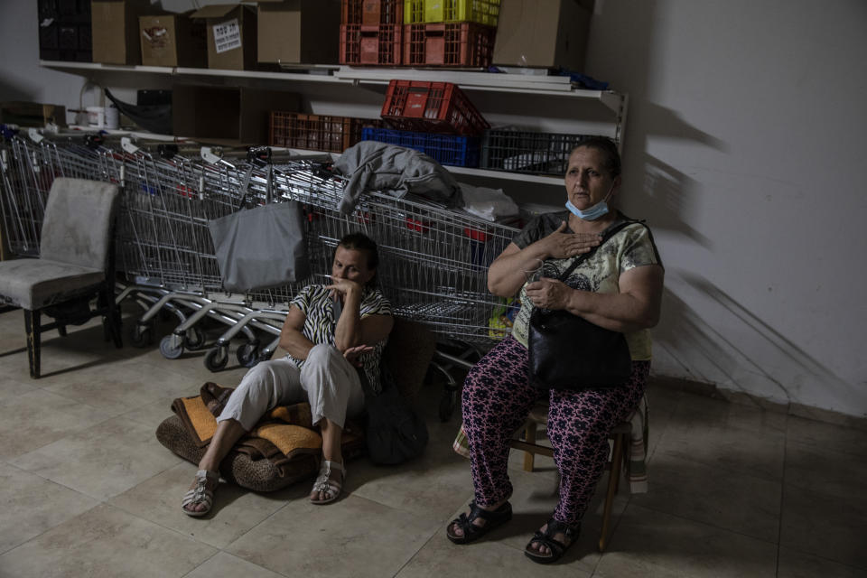 Israeli Kassadra Bodari, left, and Lilian Feciouru take shelter in Ashdod, Israel during sirens warning of incoming rockets fired from Gaza Strip, Tuesday, May 18, 2021. (AP Photo/Heidi Levine)