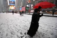 People walk through falling snow through Times Square in New York, January 26, 2015. REUTERS/Mike Segar