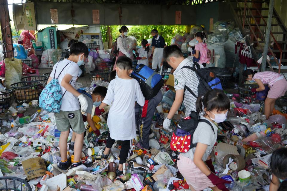 離開了有冷氣的教室，「資源分類體驗」分為四組，來到環保站內的實作區進行實作，然而暑熱的高溫天氣，還沒動手做，已讓大家額頭開始冒汗了！活潑好動的孩子們卻顯得興致勃勃，有人踩寶特瓶、也有人進行分類。