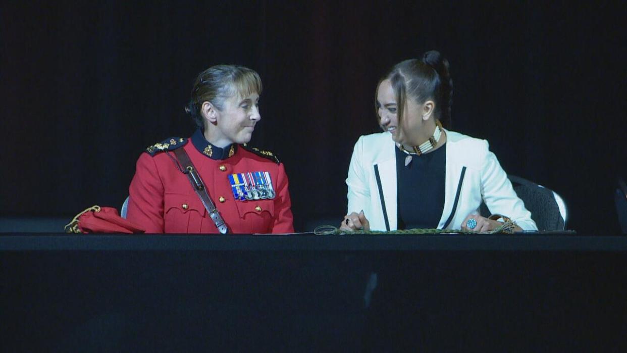 RCMP Assistant Commissioner Rhonda Blackmore, left, and Federation of Sovereign Indigenous Nations third vice-chief Aly Bear sign an agreement Friday to improve communication between police and First Nation communities in Saskatchewan. (CBC News - image credit)