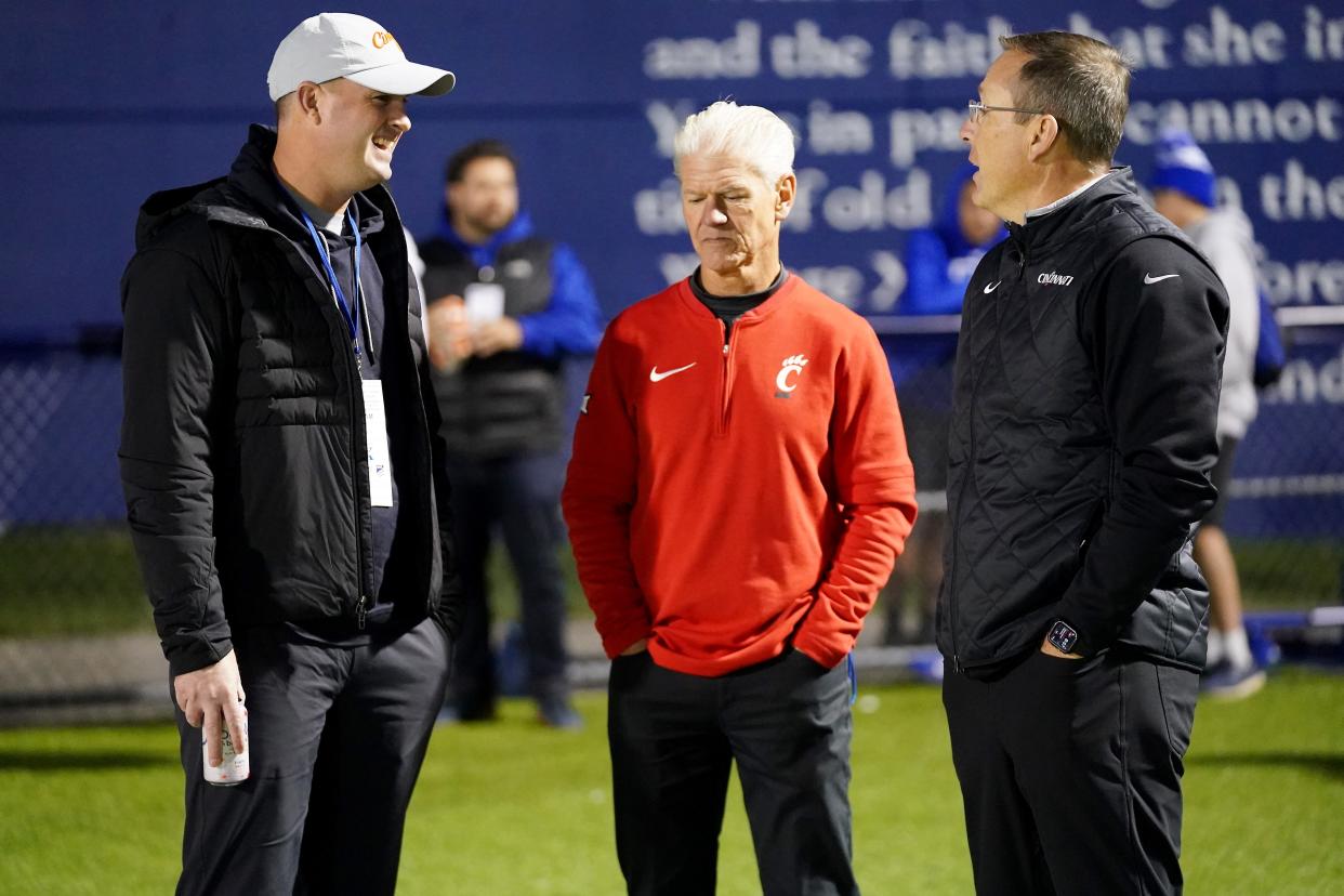 Cincinnati Bengals head coach Zac Taylor, left, talks with Cincinnati Bearcats special teams coordinator and secondary coach Kerry Coombs, center, and head coach Scott Satterfield, right, in the first half of a second-round Division I OHSAA high school football game between the Moeller Crusaders and the St. Xavier Bombers, Friday, Nov. 3, 2023, at St. Xavier High School’s RDI Field in Cincinnati.