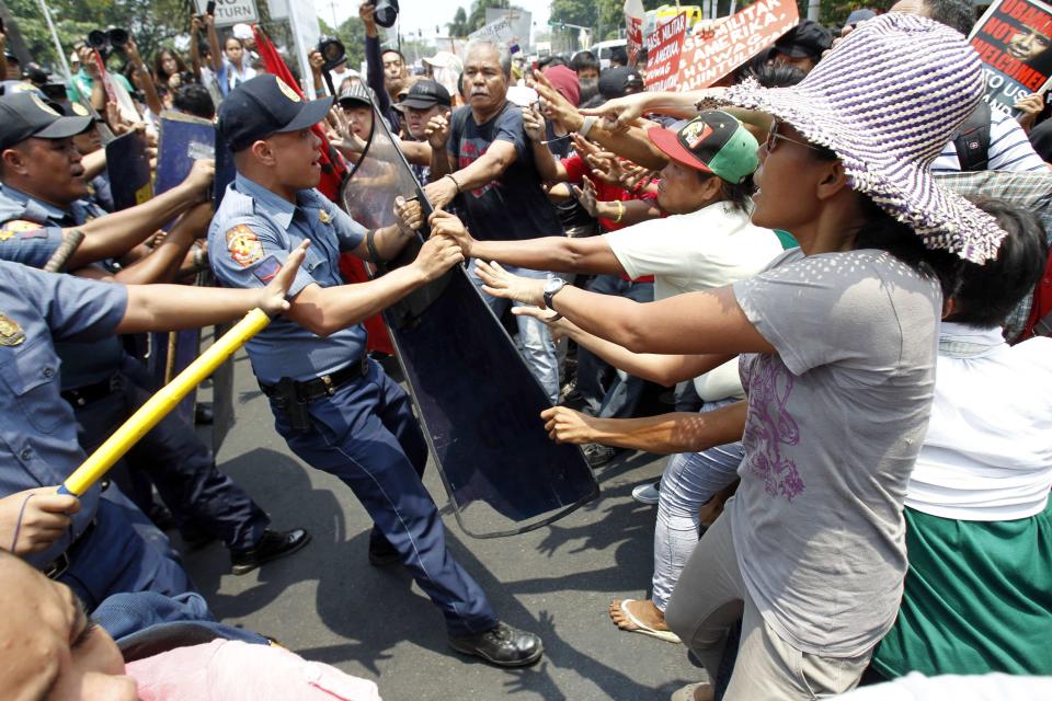 Protesters grab the shield of an anti-riot policeman during a protest against the upcoming visit of U.S. President Barack Obama next week, in front of the U.S. embassy in Manila April 23, 2014.