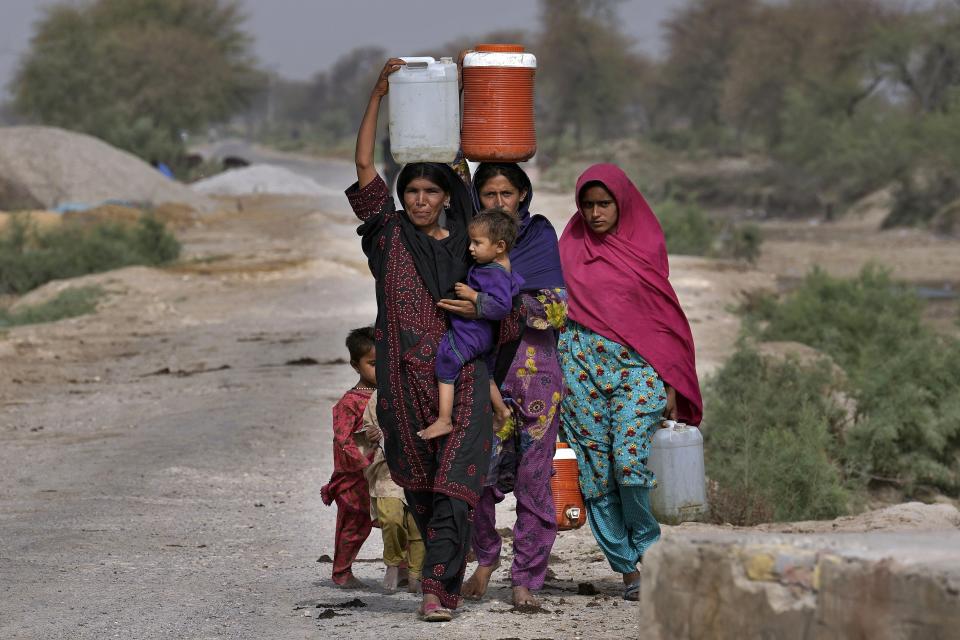 Women carry canisters to their tents after getting water from a nearby hand pump, in Ismail Khan Khoso village in Sohbatpur, a district of Pakistan's Baluchistan province, Thursday, May 18, 2023. (AP Photo/Anjum Naveed)