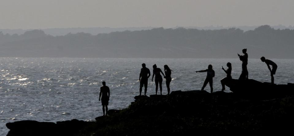 People along the rocky shoreline at Brenton Point in Newport.