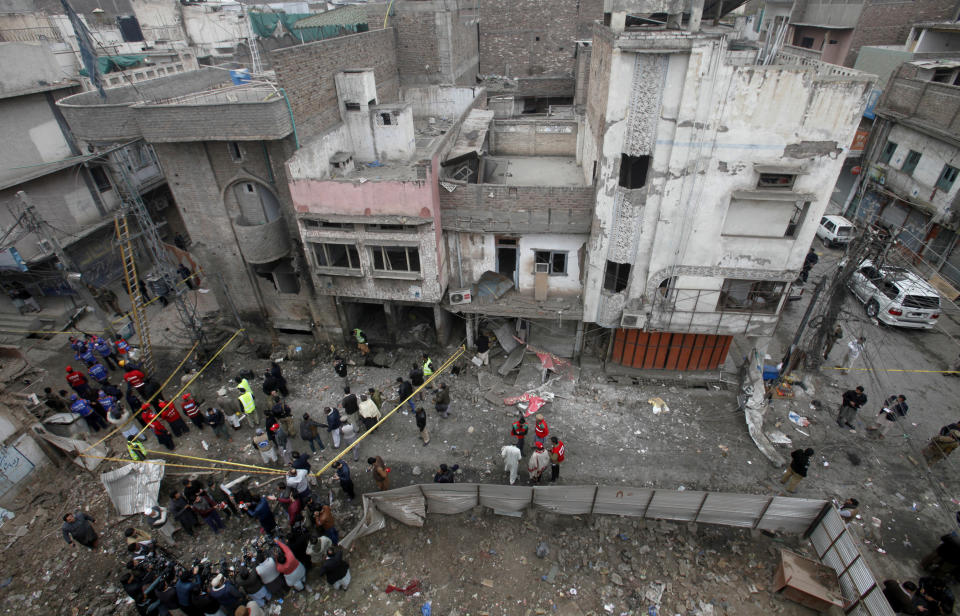 Pakistani police officers and rescue workers gather at the site of bomb blast in Peshawar, Pakistan, Saturday, Jan. 5, 2019. Pakistani police say a car bomb exploded in a Peshawar neighborhood wounding three people and damaging several shops. (AP Photo/Mohammad Sajjad)