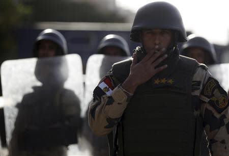 An Egyptian army officer smokes a cigarette while standing guard with armoured personnel carriers (APC) during a protest by members of the Muslim Brotherhood and supporters of ousted Egyptian President Mohamed Mursi, near Rabaa al-Adawiya square in Cairo's Nasr City district, October 4, 2013. REUTERS/Amr Abdallah Dalsh