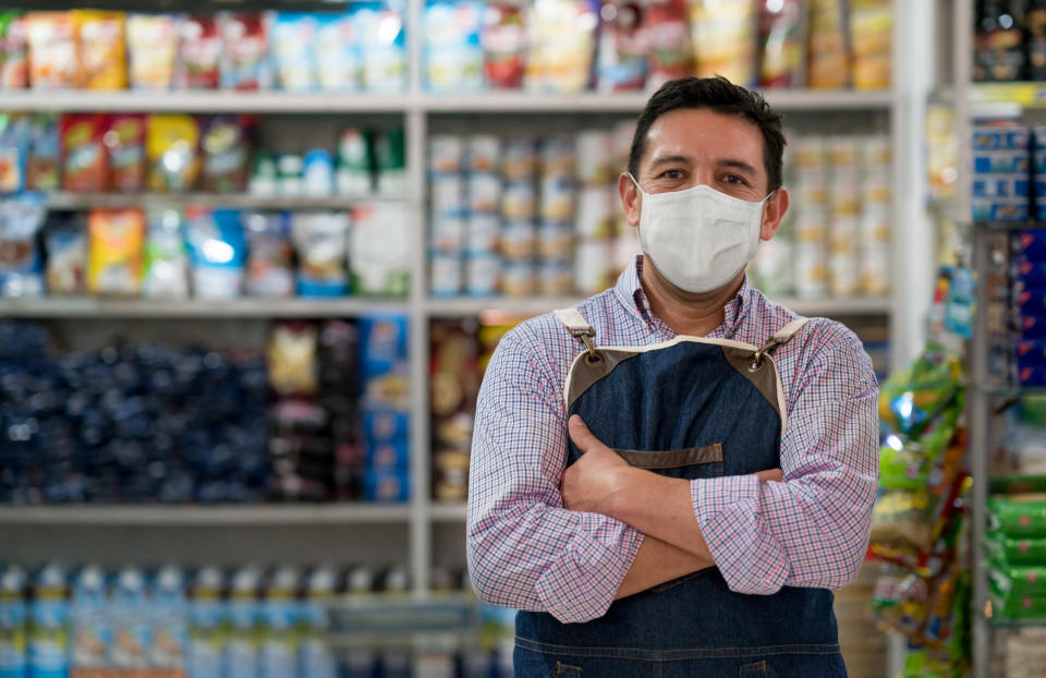 Business owner working at a grocery store wearing a facemask to avoid the coronavirus - pandemic lifestyle concepts