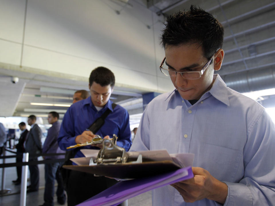 In this Wednesday, Oct. 24, 2012 photo, Fabio Magliano, right, fills out a job application as he stands in line at a job fair in Miami. According to government reports released Friday, Nov. 2, 2012, the U.S. economy added 171,000 jobs in October, and the unemployment rate ticked up to 7.9 percent. (AP Photo/Alan Diaz)