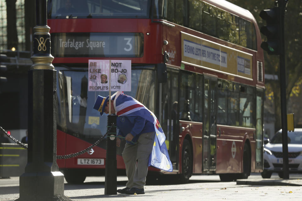 A demonstrator attaches a banner outside the Houses of Parliament in London, Wednesday, Nov. 14, 2018. British Prime Minister Theresa May will try to persuade her divided Cabinet on Wednesday that they have a choice between backing a draft Brexit deal with the European Union or plunging the U.K. into political and economic uncertainty. (AP Photo/Tim Ireland)