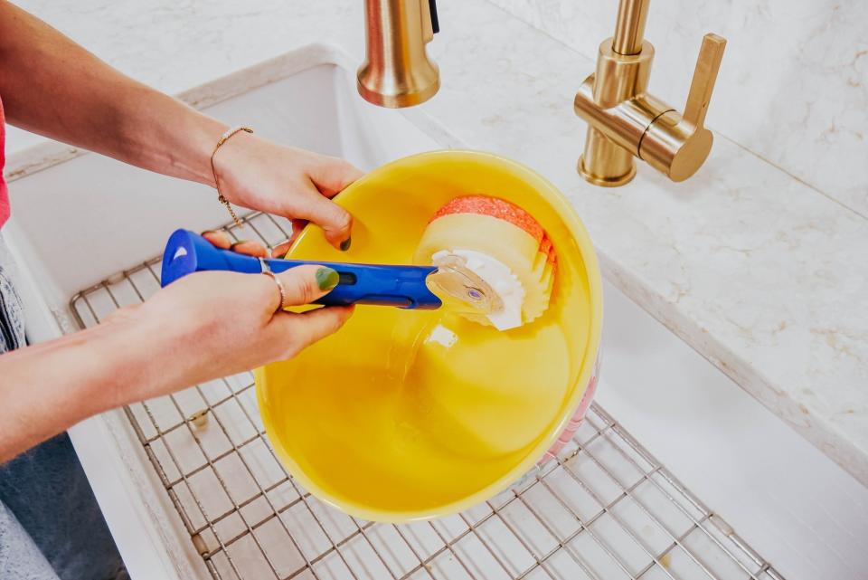 someone using the scrub daddy wand to clean a bowl