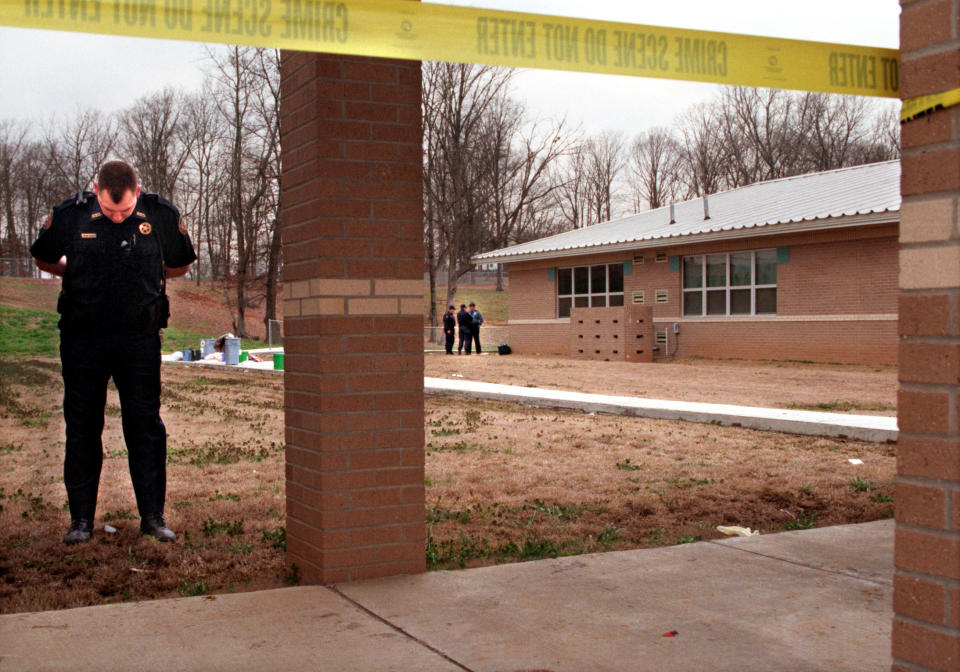 A police officer stands at the perimeter of the crime scene