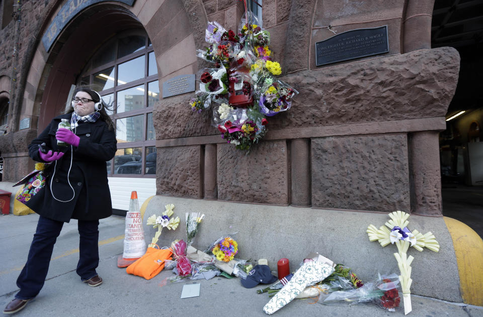 FILE - Erin Defuria, of Boston, is emotional after placing flowers at a makeshift memorial in the front of fire station Engine 33/Ladder 15, March 27, 2014, in Boston. Engine 33/Ladder 15 was the station of fallen firefighters Lt. Edward Walsh and Michael Kennedy. A decade after the two firefighters died when they became trapped in the brownstone in Boston’s historic Back Bay neighborhood by a fire caused by sparks from welders working on a building next door, the Massachusetts Senate passed a bill Thursday, March 28, 2024, aimed at toughening oversight of so-called “hot work." (AP Photo/Steven Senne, File)