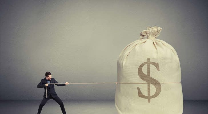 a man in a suit pulling a large bag of money with a rope