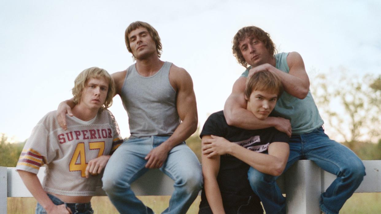 fictionalized von erich brothers from the iron claw posing for a photo in front of a white fence