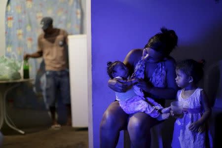 Rosana Vieira Alves holds her 4-month-old daughter Luana Vieira, who was born with microcephaly, as her daughter Laiane Sophia looks on at their home in Olinda, Brazil, February 2, 2016. REUTERS/Ueslei Marcelino