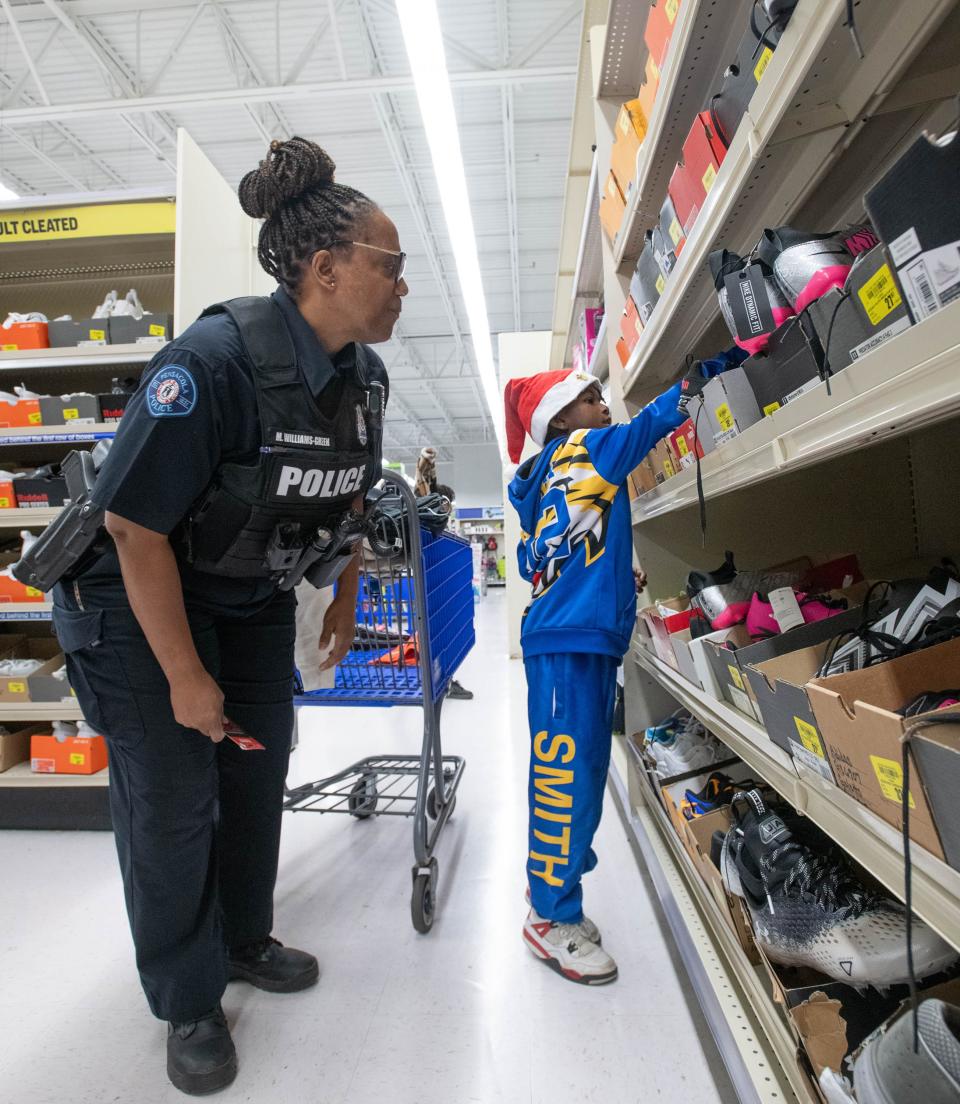 Christian Smith, 8, right, gets help picking out sneakers from Pensacola Police Department Officer Sharesea Williams-Green during the Shop with a Cop shopping spree at the Academy Sports + Outdoors in Pensacola on Thursday, Dec. 21, 2023.