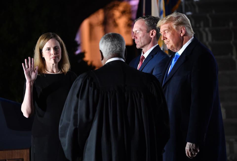 President Donald Trump watches as Supreme Court Associate Justice Clarence Thomas swears in Amy Coney Barrett as a Supreme Court Associate Justice, flanked by her husband Jesse M. Barrett, during a ceremony on the South Lawn of the White House October 26, 2020, in Washington, D.C.