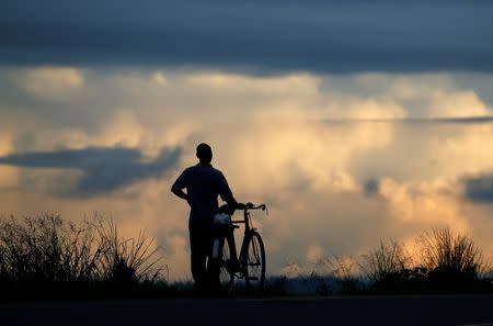 Storm clouds loom as a cyclist makes his way home near the capital Lilongwe, Malawi February 2, 2016. REUTERS/Mike Hutchings