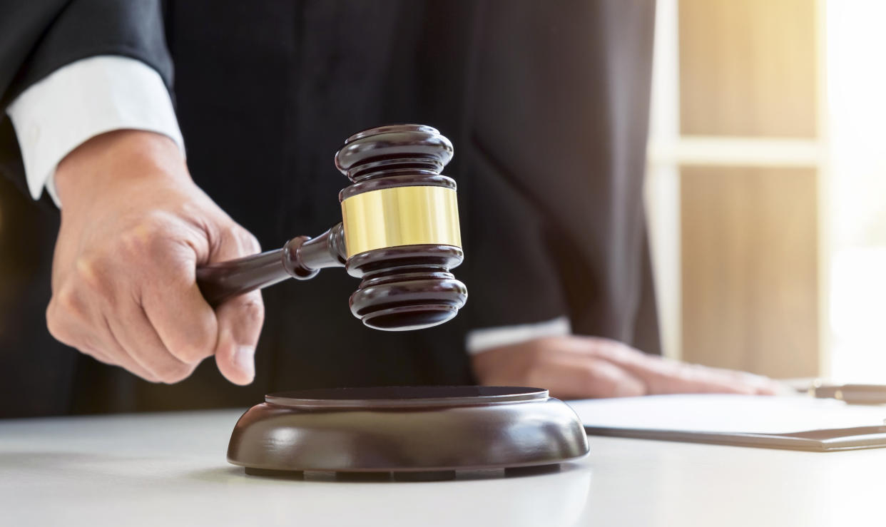 Close up of Male lawyer or judge hand's striking the gavel on sounding block, working with Law books, report the case on table in modern office, Law and justice concept.