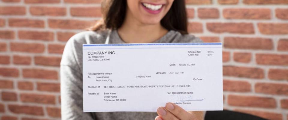 Close-up Of A Smiling Woman Showing Company Cheque