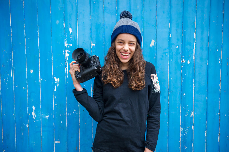 Girl with camera against blue wooden panelling background