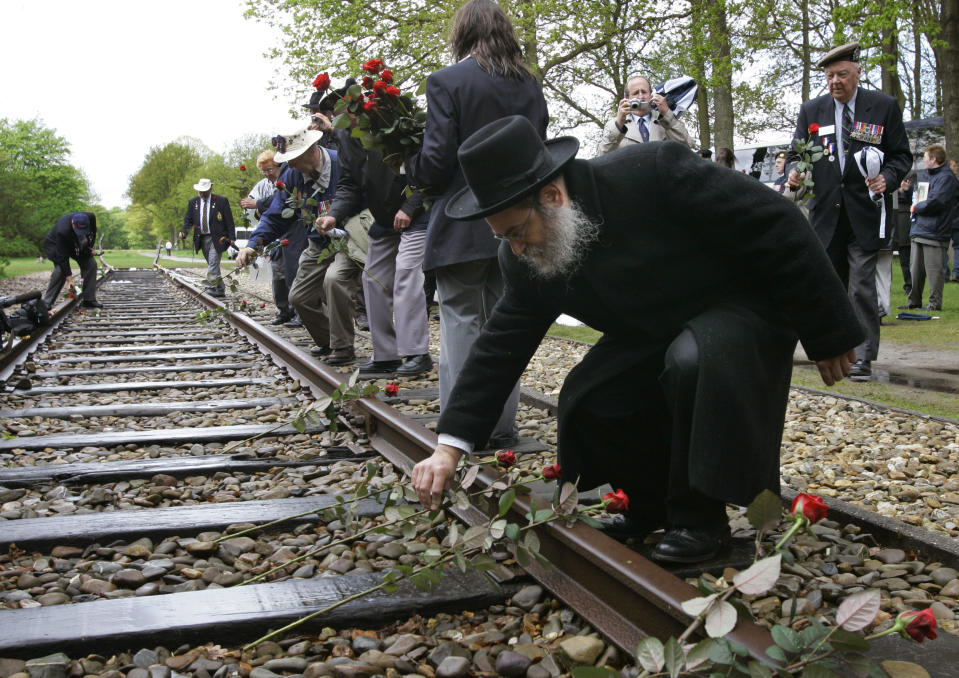 In this Monday May 9, 2015, file photo, a Rabbi puts a rose on the railroad tracks at former concentration camp Westerbork, the Netherlands, remembering more than a hundred thousand Jews who were transported from Westerbork to Nazi death camps. The Dutch national railway company NS says it will set up a commission to investigate how it can pay individual reparations for its role in mass deportations of Jews by Nazi occupiers during World War II. (AP Photo/Peter Dejong)