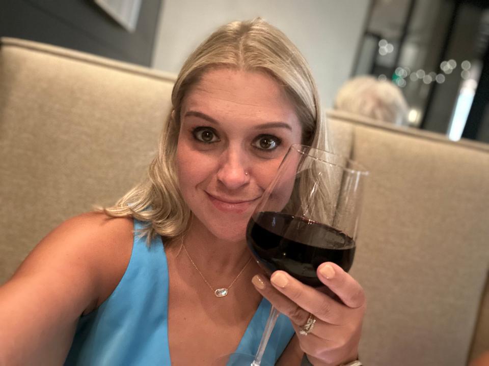 Terri Peters holding a glass of red wine and smiling