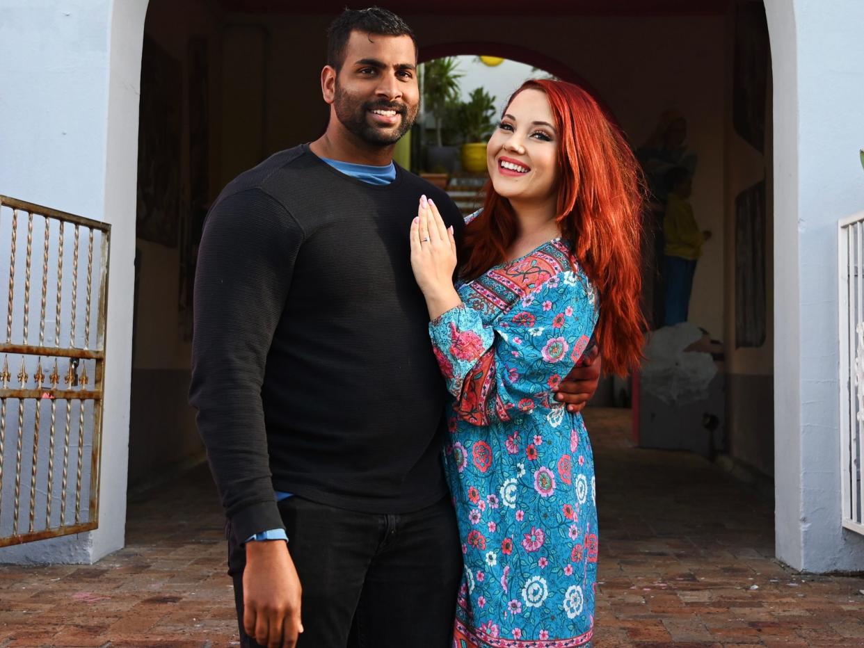 Megan Gieske and her partner smiling in front of pink building