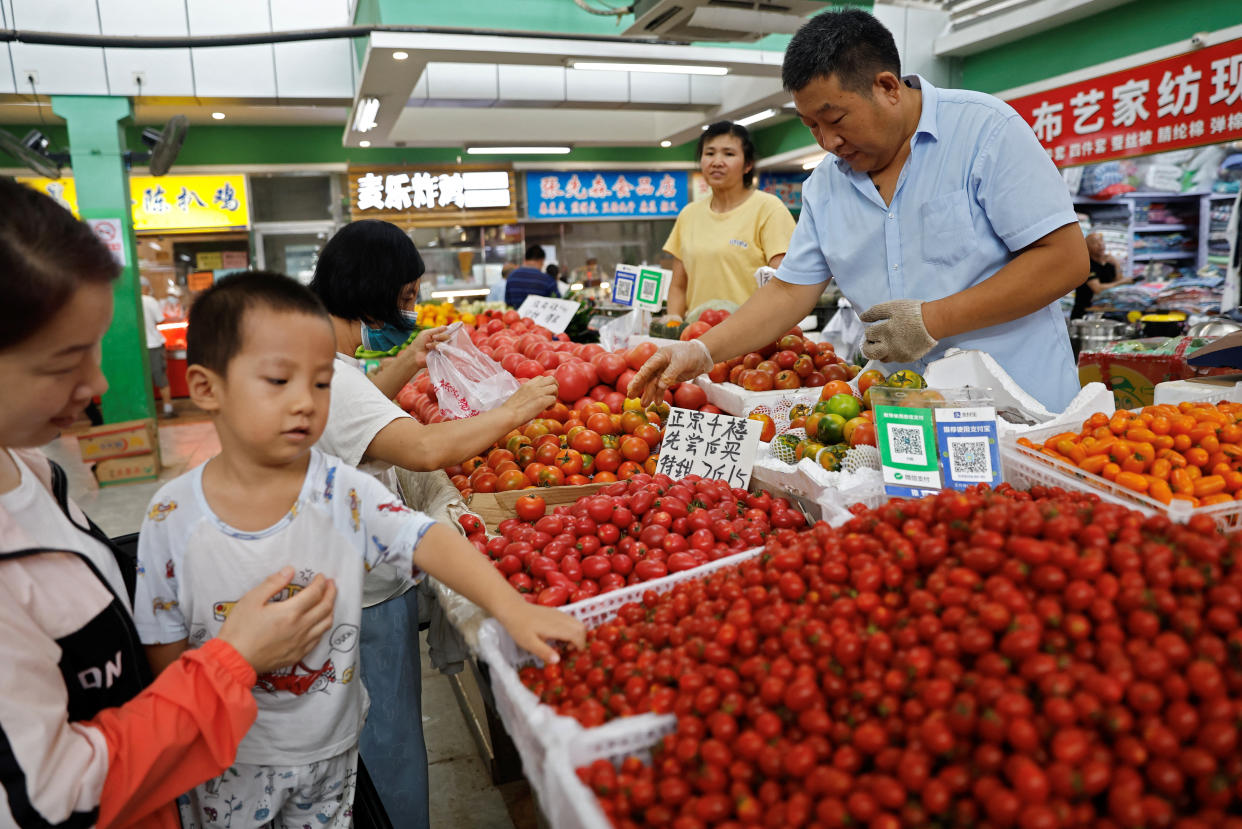 Customers select tomatoes at a stall inside a morning market in Beijing, China August 9, 2023. REUTERS/Tingshu Wang