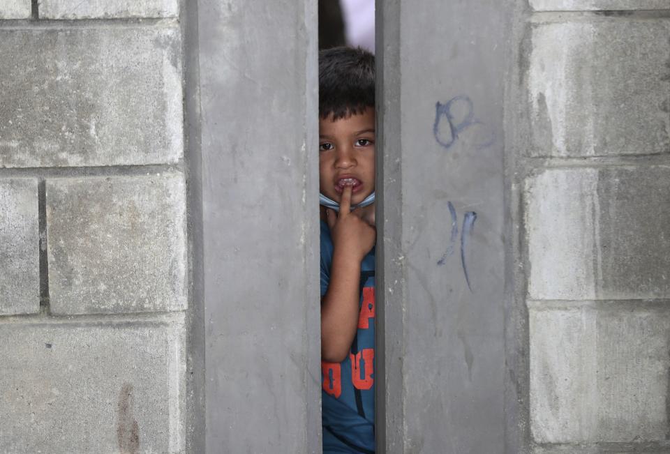 A boy peers from a migrant shelter in Arauquita, Colombia, Thursday, March 25, 2021, on the border with Venezuela. Thousands of Venezuelans are seeking shelter in Colombia this week following clashes between Venezuela's military and a Colombian armed group in a community along the nations' shared border. (AP Photo/Fernando Vergara)