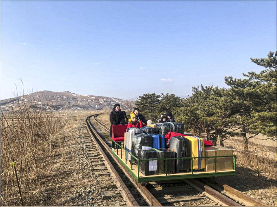 In this image taken from a video released by Russian Foreign Ministry Press Service Thursday, Feb. 25, 2021, a group of Russian diplomats push hand-pushed rail trolley with their children and suitcases to the border with Russia. A group of Russian diplomats and their family members returned to Russia from North Korea on a hand-pushed rail trolley on Thursday because of COVID-19 restrictions in the country, Russia's Foreign Ministry said in a Facebook post. (Russian Foreign Ministry Press Service via AP)