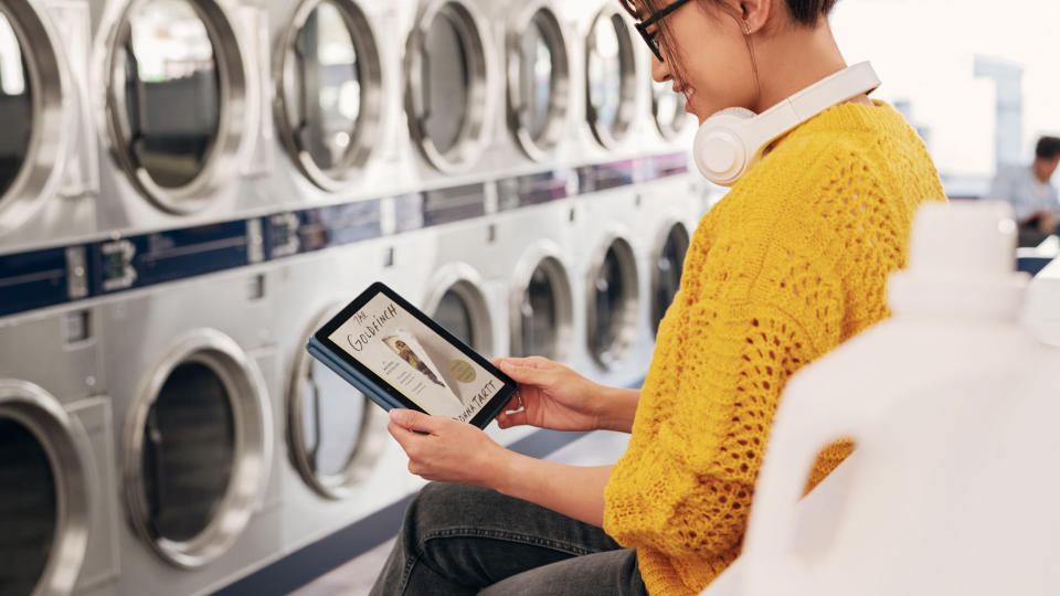 Kindle vs Fire: A woman uses the Fire HD 10 to read in a laundromat