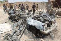 Iraqi fighters from the Shiite popular mobilisation unit walk past a destroyed vehicle near the Baiji refinery north of Tikrit, on May 25, 2015