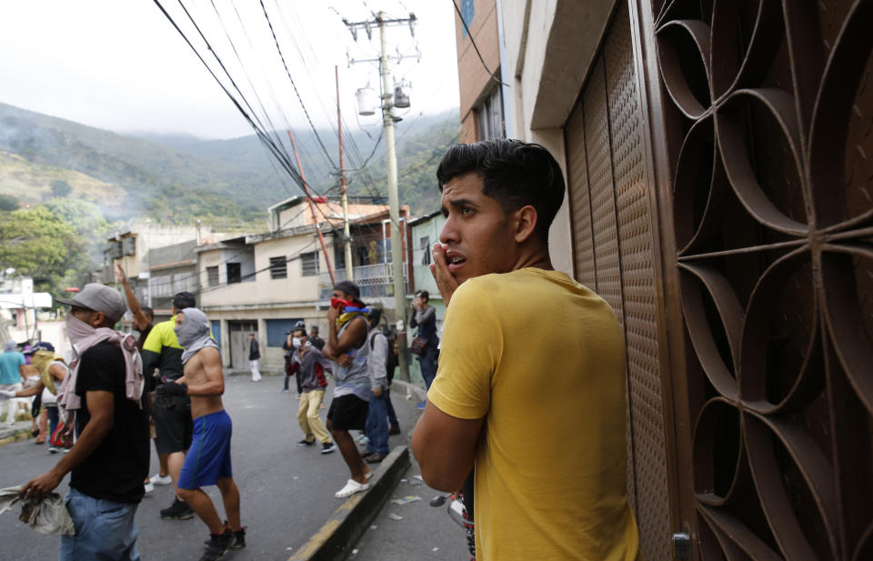 Un joven observa mientras manifestantes opositores al gobierno se enfrentan con elementos de seguridad después de una aparente sublevación por parte de elementos de la Guardia Nacional en el barrio Cotiza, en Caracas, Venezuela, el lunes 21 de enero de 2019. (AP Foto/Ariana Cubillos)