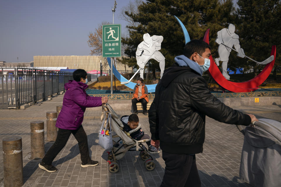 Residents walk by a barricaded venue which host the men's and women's ice hockey games at the 2022 Winter Olympics in Beijing, Thursday, Feb. 10, 2022. The possibility of a large outbreak in the Olympic bubble, potentially sidelining athletes from competitions, has been a greater fear than any leakage into the rest of China. (AP Photo/Andy Wong)