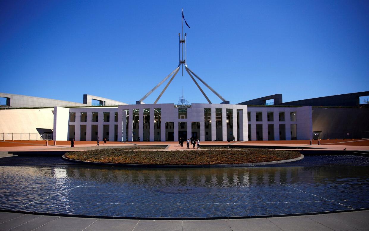 Tourists walk around the forecourt of Australia's Parliament House in Canberra - REUTERS