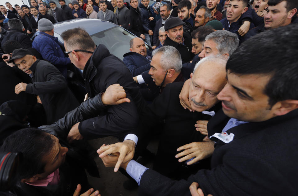 Bodyguards protect Kemal Kilicdaroglu, the leader of Turkey's main opposition Republican People's Party, as a man throws a punch toward him, during the funeral of a soldier who was slain during clashes with Kurdish rebels at Iraq border, outside Ankara, Turkey, Sunday, April 21, 201. The politician was not hurt, party officials said. Protestors at a village outside of Ankara threw punches at Kemal Kilicdaroglu as security officials tried to escort him away from the crowd, television footage showed. (DHA via AP Photo)