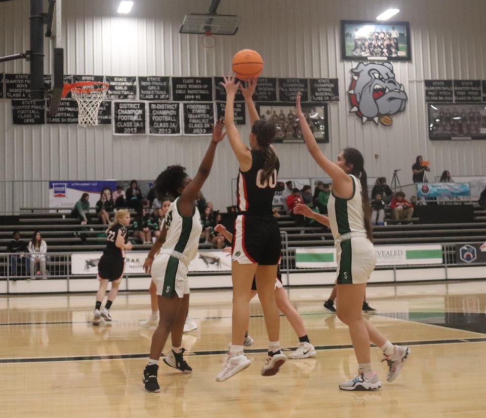 Meeker's Aviary Helms (00) delivers a jump shot between the defense of Seminole's Tanya Rideaux (left) and Annira Sewell Tuesday night in Meeker.