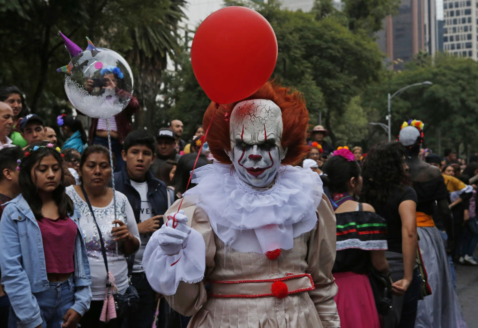 A man wears the costume of what's known as "It," a movie character, during the Catrinas parade down Mexico City's iconic Reforma avenue during celebrations for the Day of the Dead in Mexico, Saturday, Oct. 26, 2019. (AP Photo/Ginnette Riquelme)