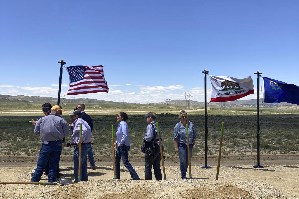 U.S. Interior Secretary Deb Haaland, center, takes part in a groundbreaking ceremony Tuesday, June 20, 2023, for the TransWest Express transmission line south of Rawlins, Wyo. The transmission line will partly parallel the existing PacifiCorp Gateway West transmission system, seen in the background, moving electricity from a planned 600-turbine wind farm to California. Wyoming is having a wind energy boom that could help alleviate climate change but is raising worries among residents that proliferating wind turbines will spoil views, disturb wildlife and kill birds. (AP Photo/Mead Gruver)