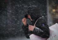 A woman covers her face from heavy falling snow as she makes her way through Times Square in New York January 26, 2015. REUTERS/Mike Segar